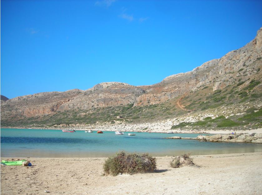 Απεικονίζεται η παραλία του Μπάλου και απέναντι φαίνονται τα βράχια